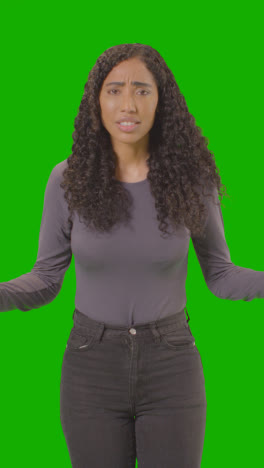 Vertical-Video-Three-Quarter-Length-Shot-Of-Angry-Looking-Vertical-Video-Woman-Shouting-At-Camera-Against-Green-Screen